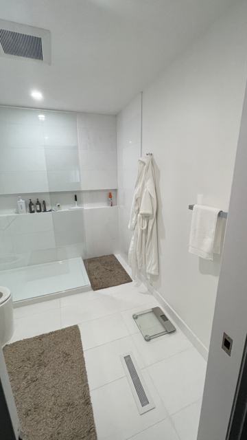 Bathroom with tiled shower, glass enclosure and white vanity