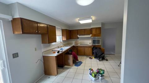 Before: kitchen with wood cabinets and tile floor, photographed during the work