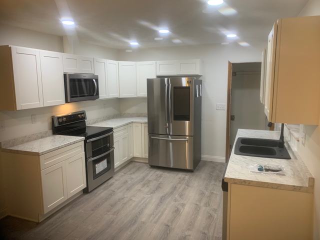 Kitchen with white cabinetry, stainless appliances and wood-look flooring