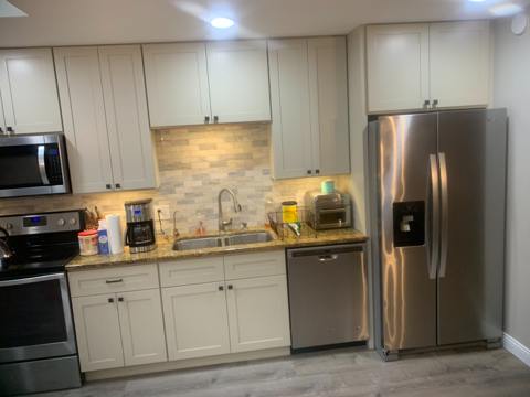 White kitchen cabinetry, patterned backsplash and stainless refrigerator