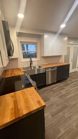 Kitchen with wood countertops, dark base cabinets and light upper cabinets