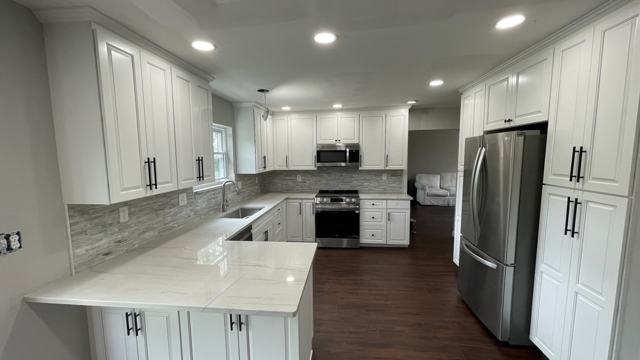 White kitchen with a peninsula, stone-look backsplash and stainless appliances