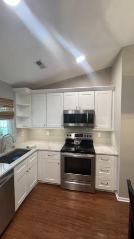 White kitchen cabinetry and stainless range beneath recessed lighting